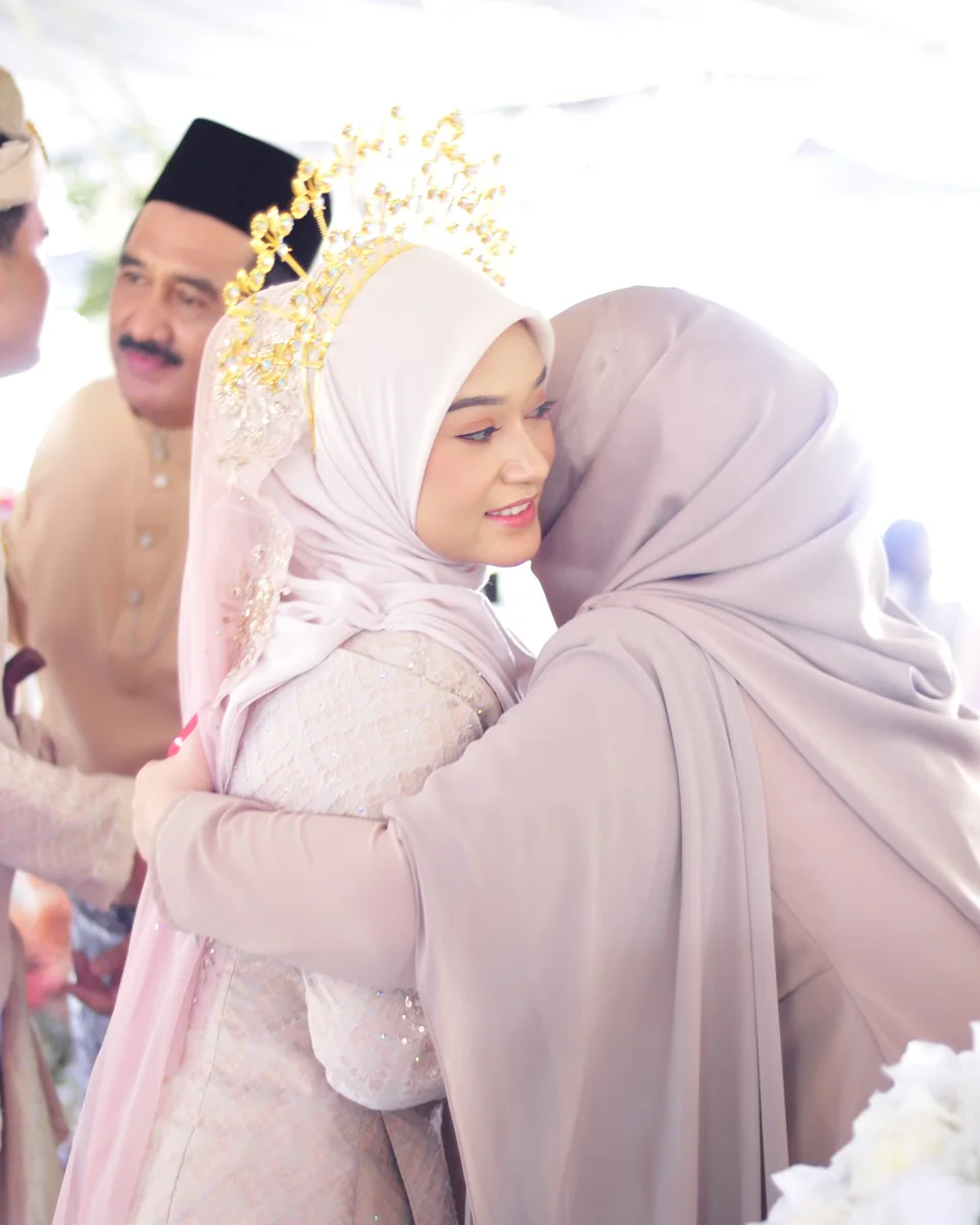 The bride being warmly embraced by a wedding guest